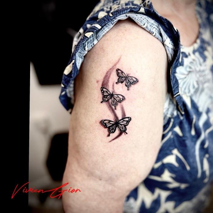 realistic tattoo of butterflies flying across the arm of women in realism
