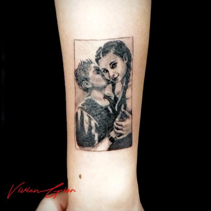  tattoo of a boy kissing a girl with watches on and girl looking at the camera tattooed on the hand 